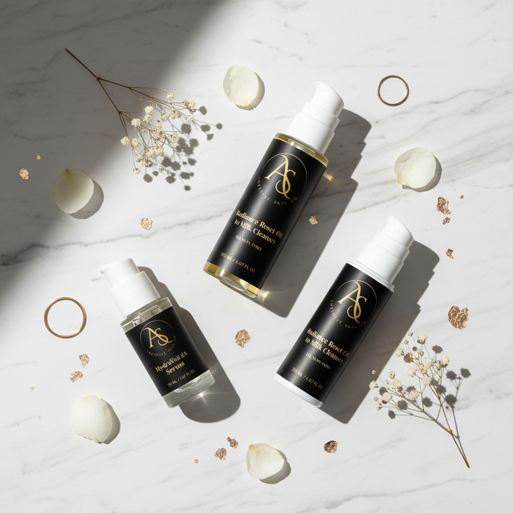 Essential Glow Ritual skincare bundle - Oil-To-Milk Cleanser, HydraVeil HA Serum, and Renewal Lift Moisturizer styled on marble surface